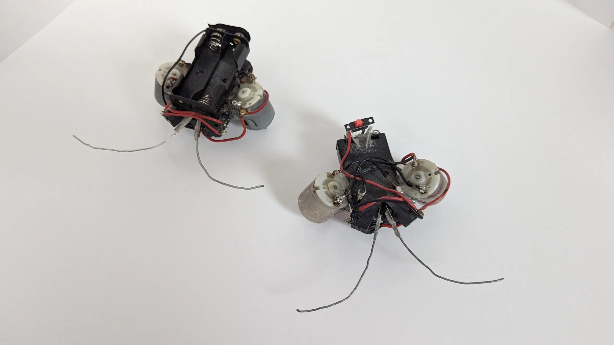 Both Beetles together on the table, showing their mirrored battery-holder chassis layouts