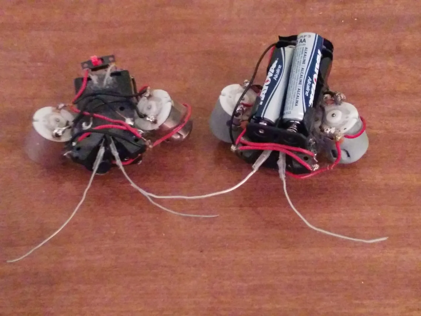 Two hand-built BEAM beetle robots side by side on a white table