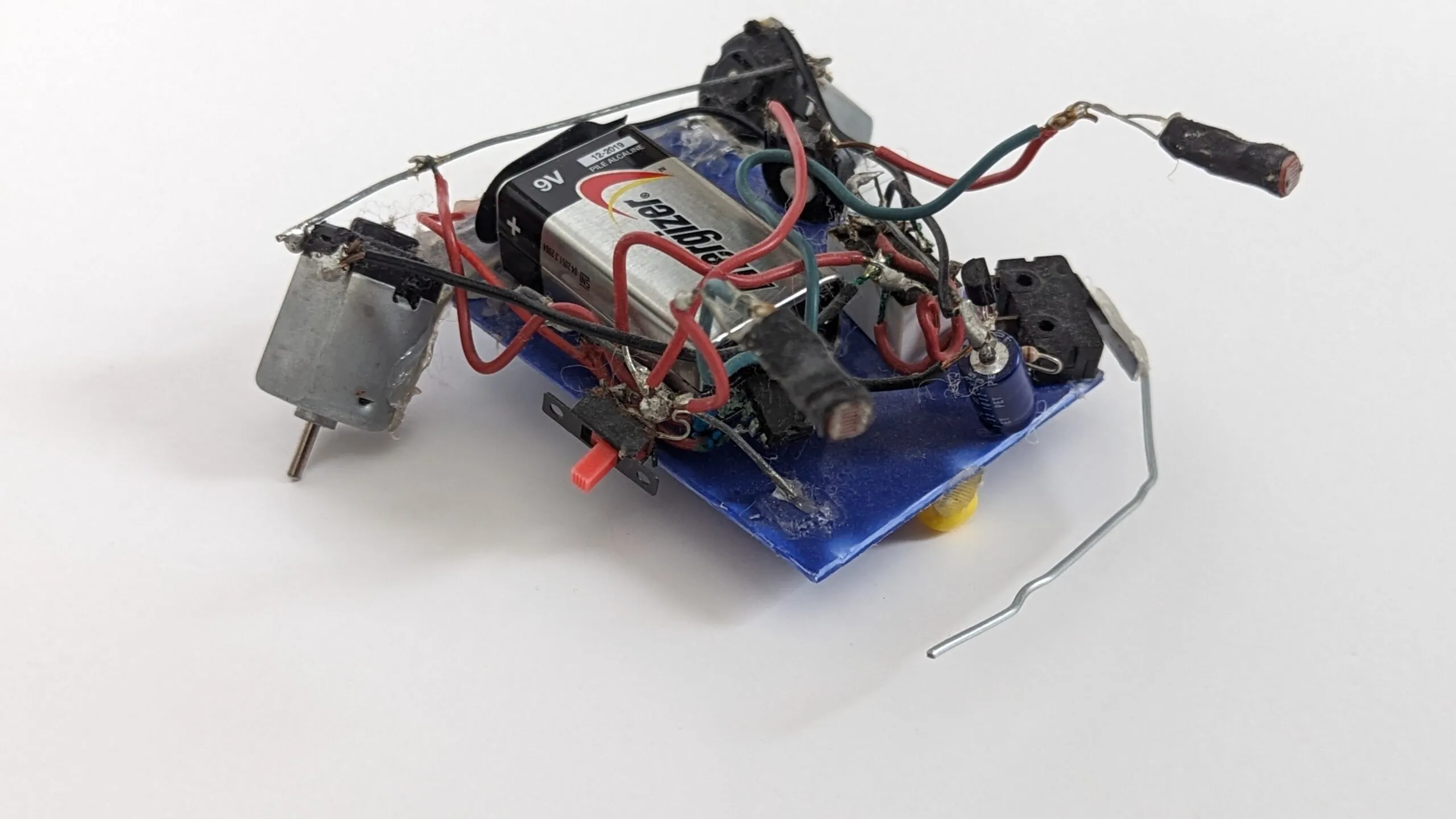Herbie today: 9V strapped over the blue chassis, drive motor on the left, photoresistors and whisker reaching forward