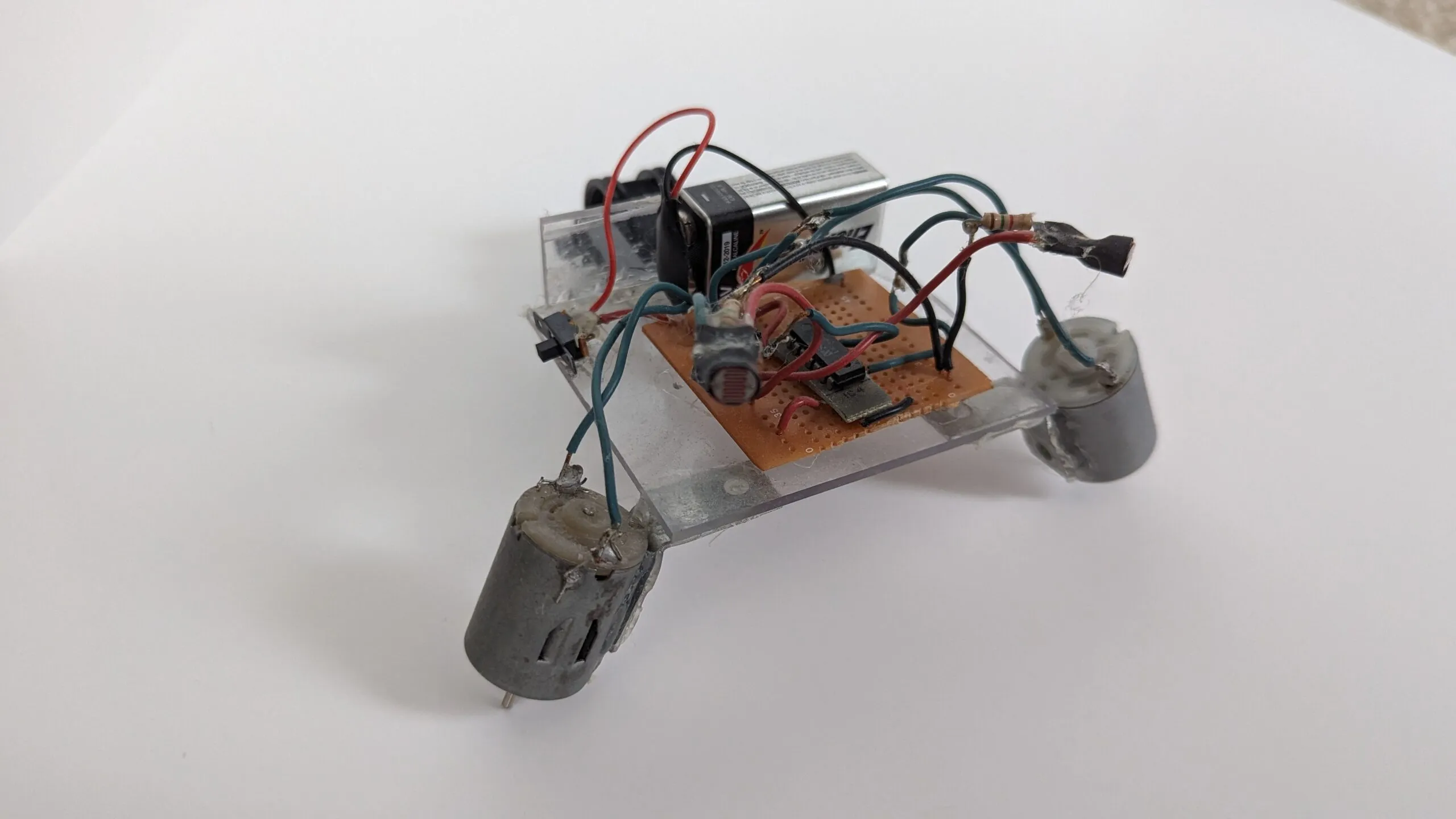 Rear three-quarter of NoBB: 9V and trim pot riding the clear chassis above the protoboard