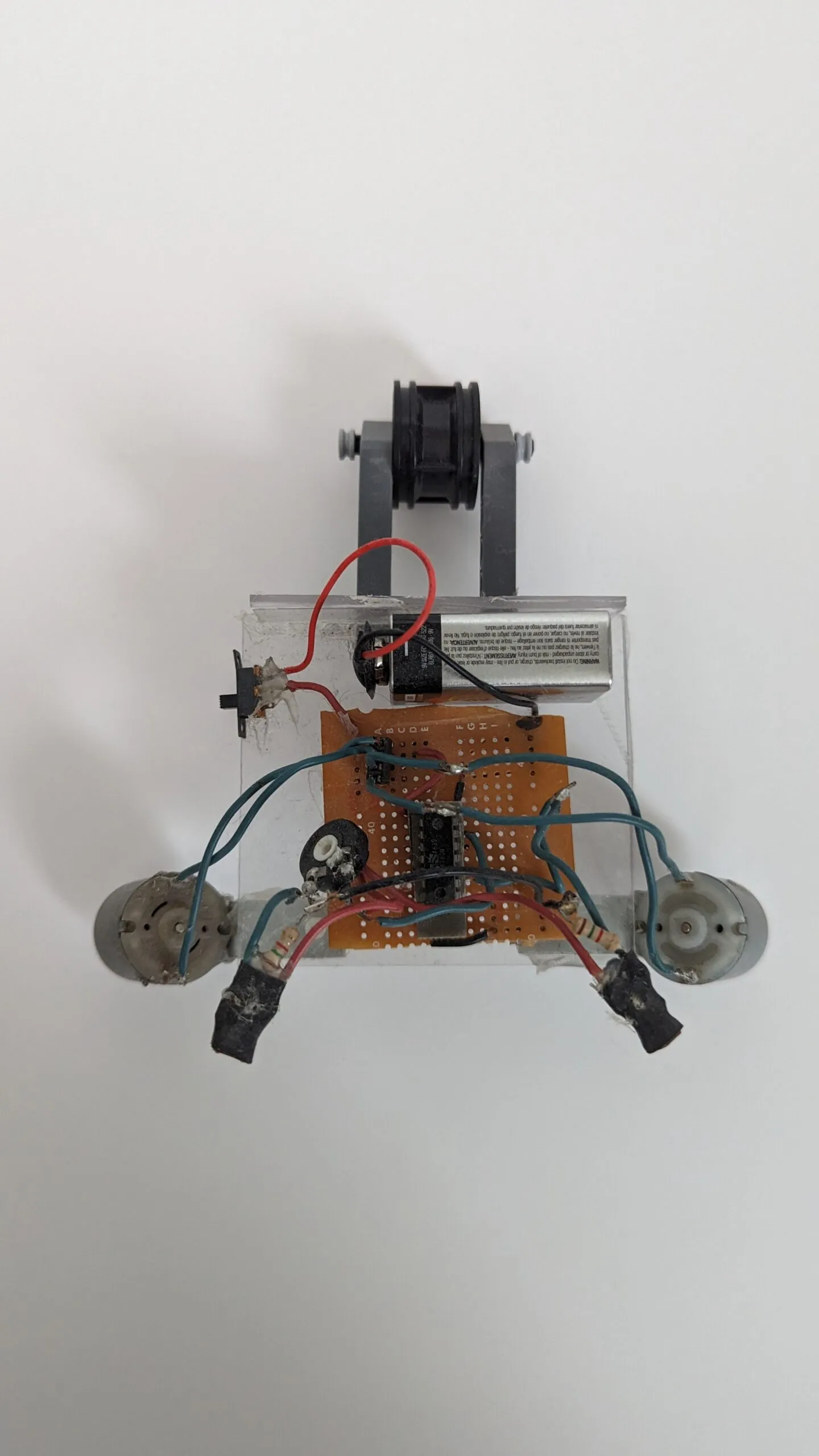 Top-down view of NoBB: LEGO caster arm out front, then the 9V, protoboard brain, and splayed motors