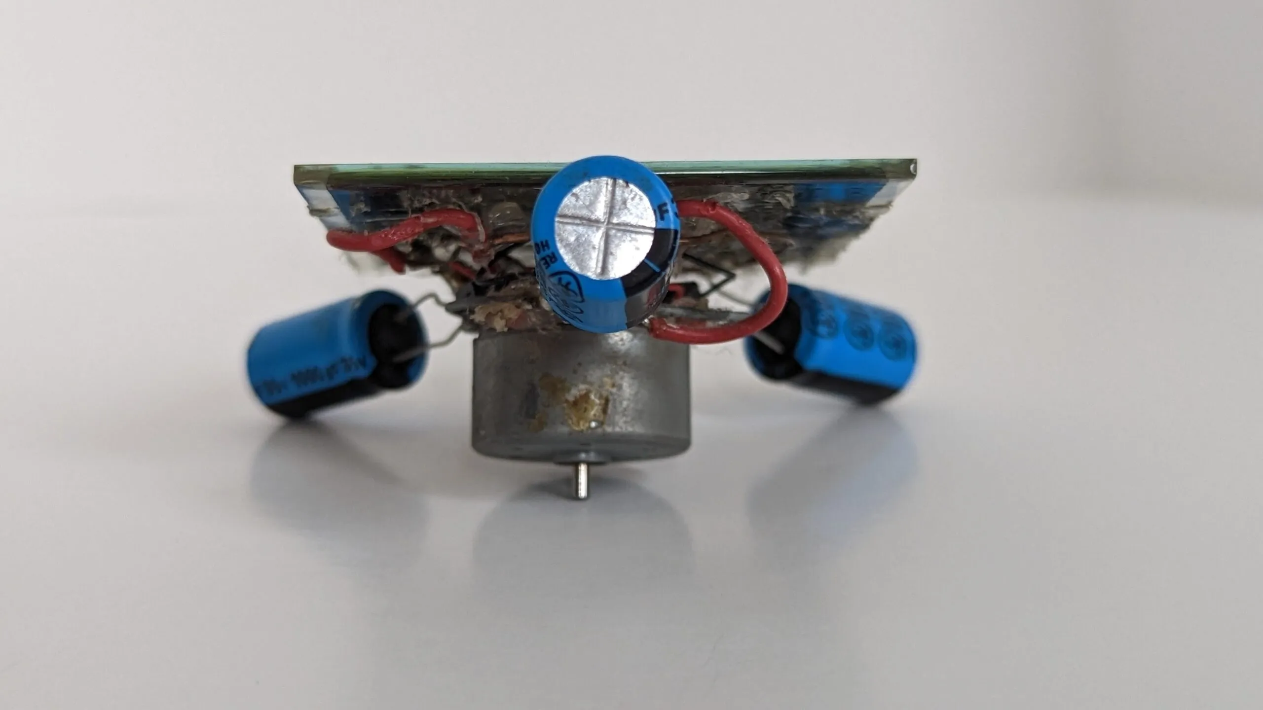 Head-on view of the Symet at table level, motor in the middle and capacitor feet splayed to both sides