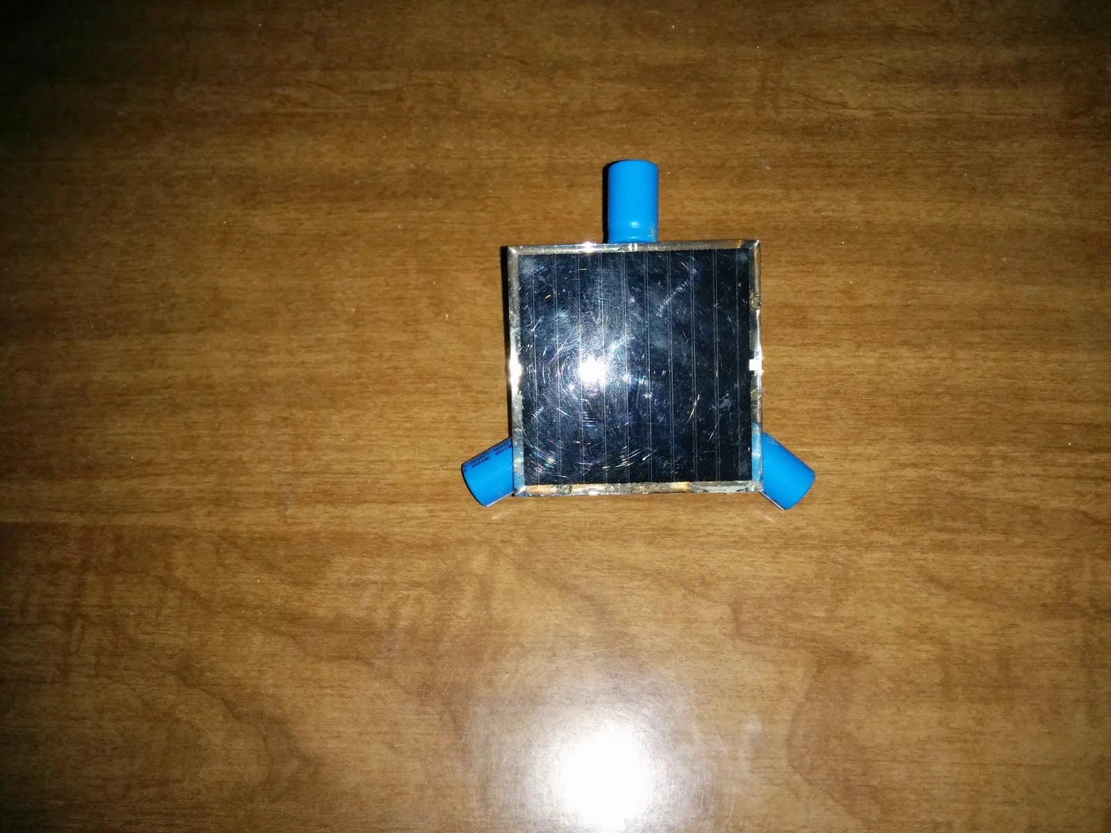 Top view of the Symet: a square solar cell balanced on three blue capacitor feet