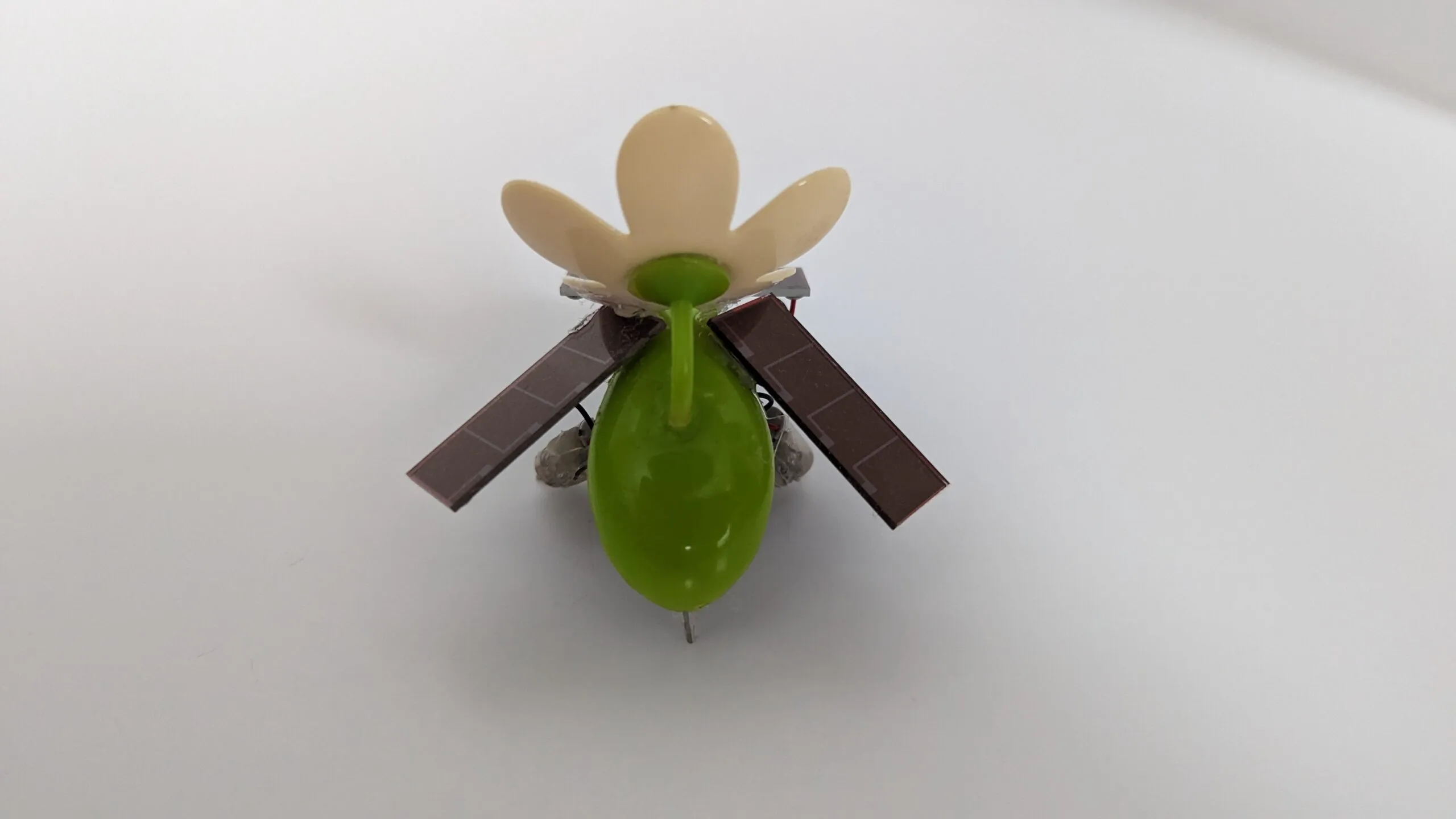 SymFlower v2 from the back, solar wings drooped like a resting moth around the green pod