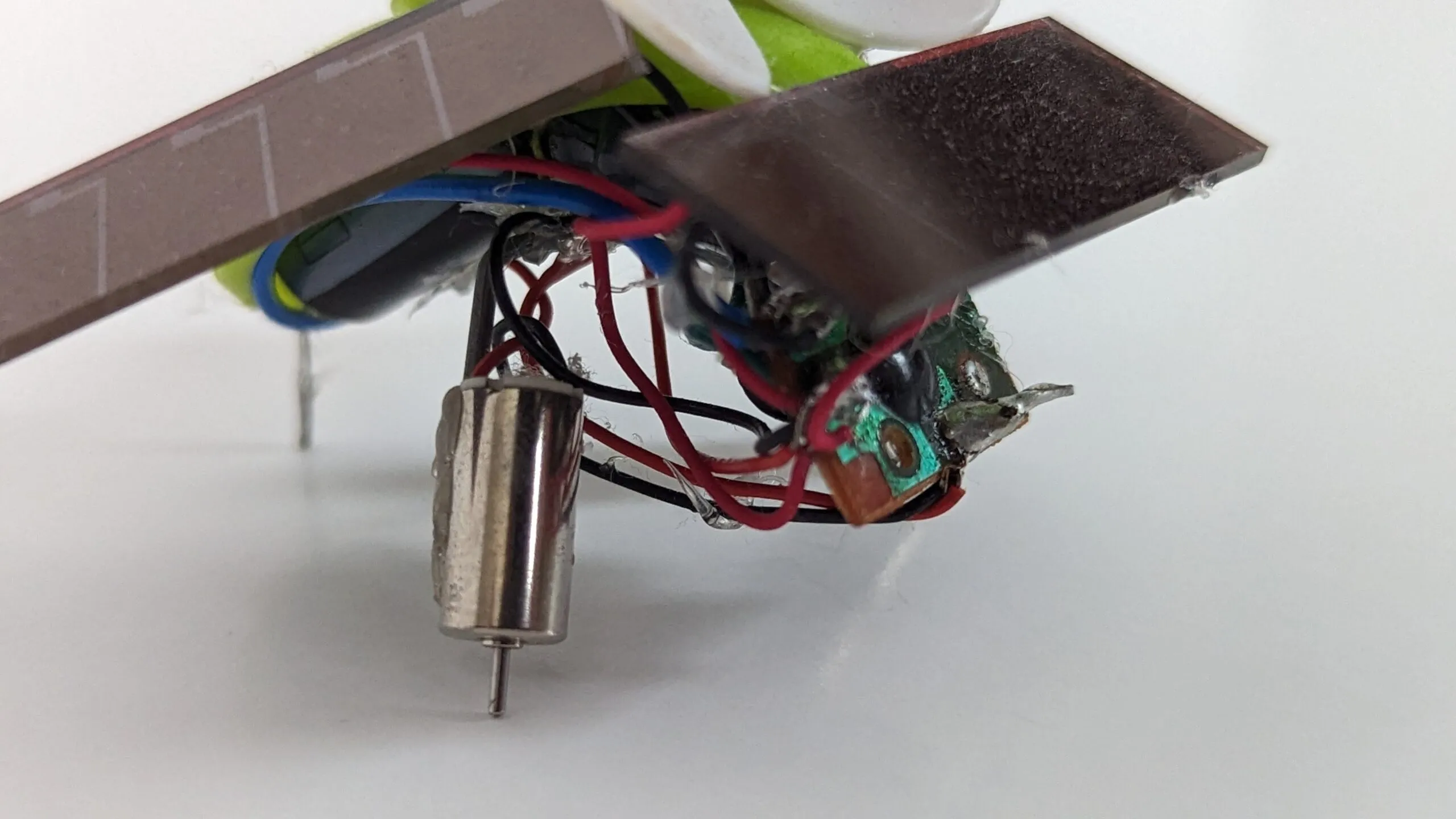 Macro of SymFlower's underside: pager motor, glue blobs, and point-to-point wiring doing structural duty