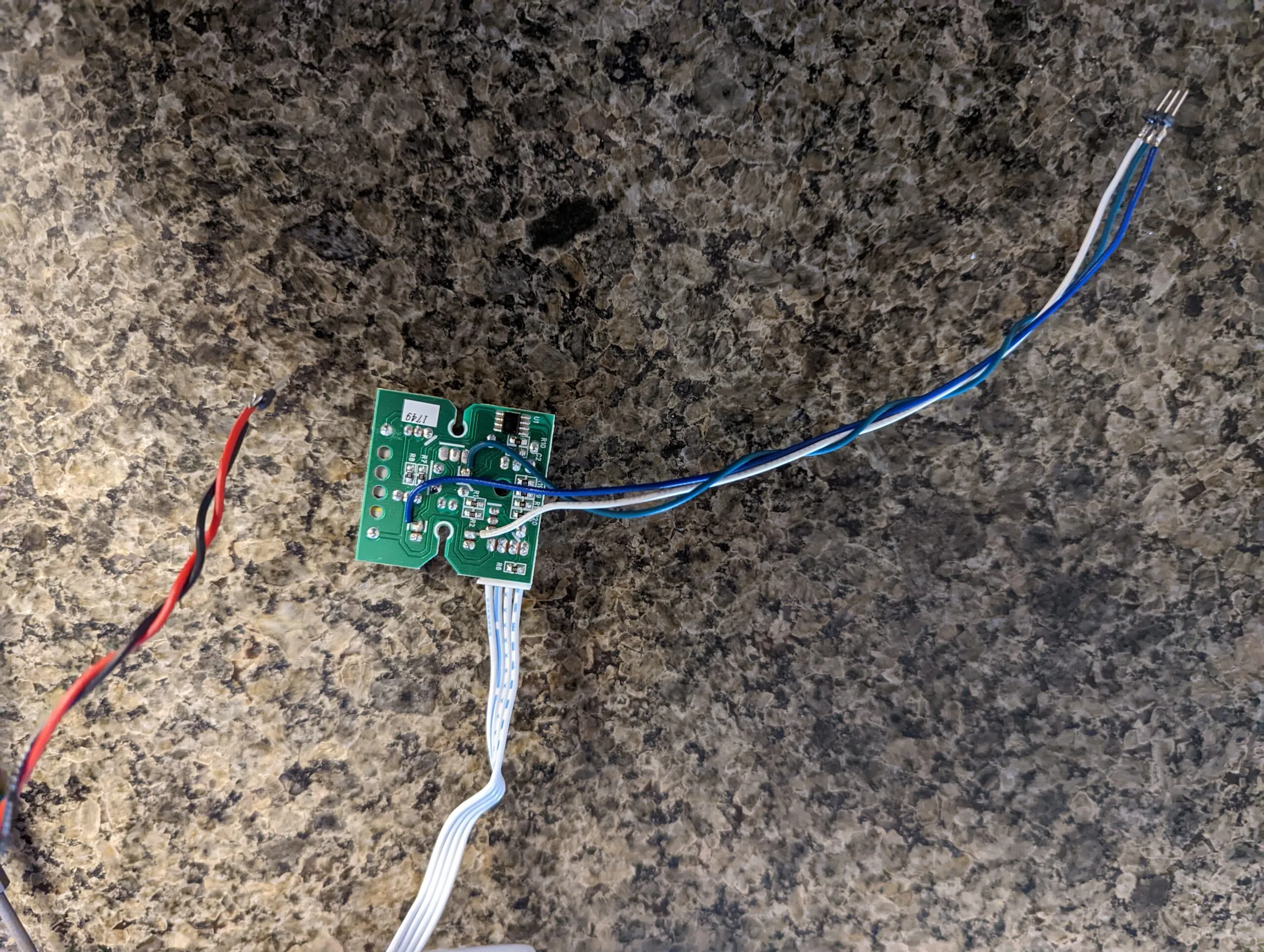 Blue and white signal leads soldered onto the board's pads and flying out to a header, the ribbon cable still attached and a red and black power pair off to the side