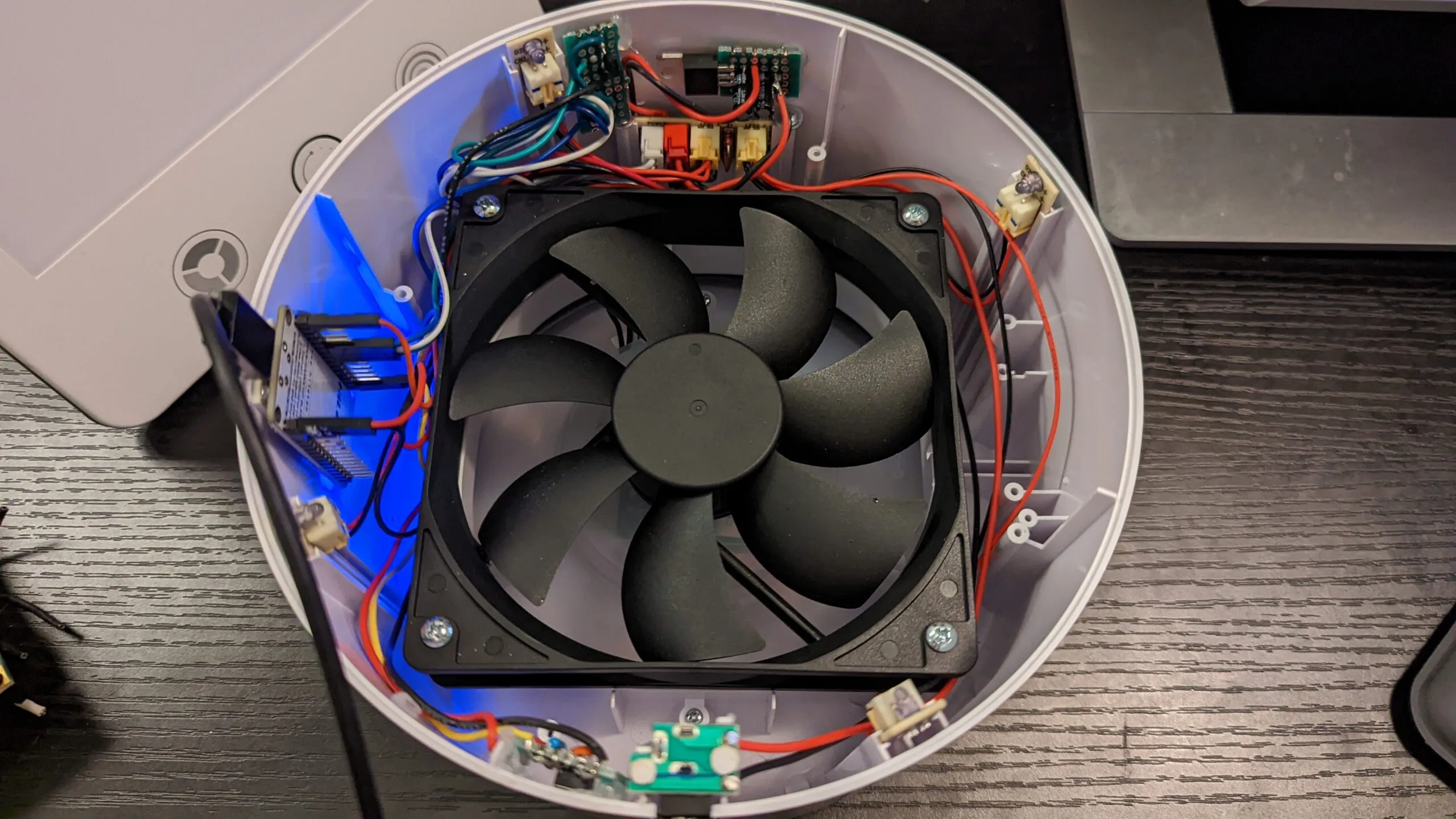 Still open and powered for flashing: a USB cable running to the NodeMCU, the ring LEDs glowing blue under the fan