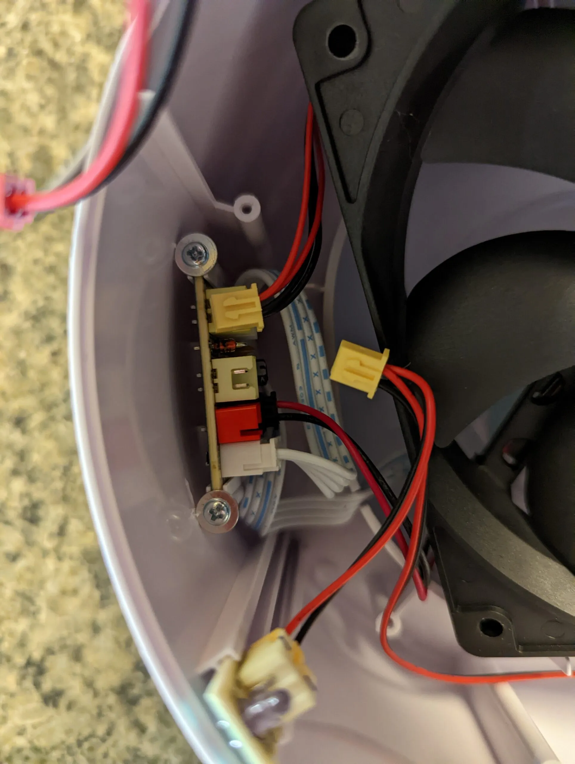 The distribution board screwed to the shell wall, a row of small connectors on it and the fan's yellow plug pulled free