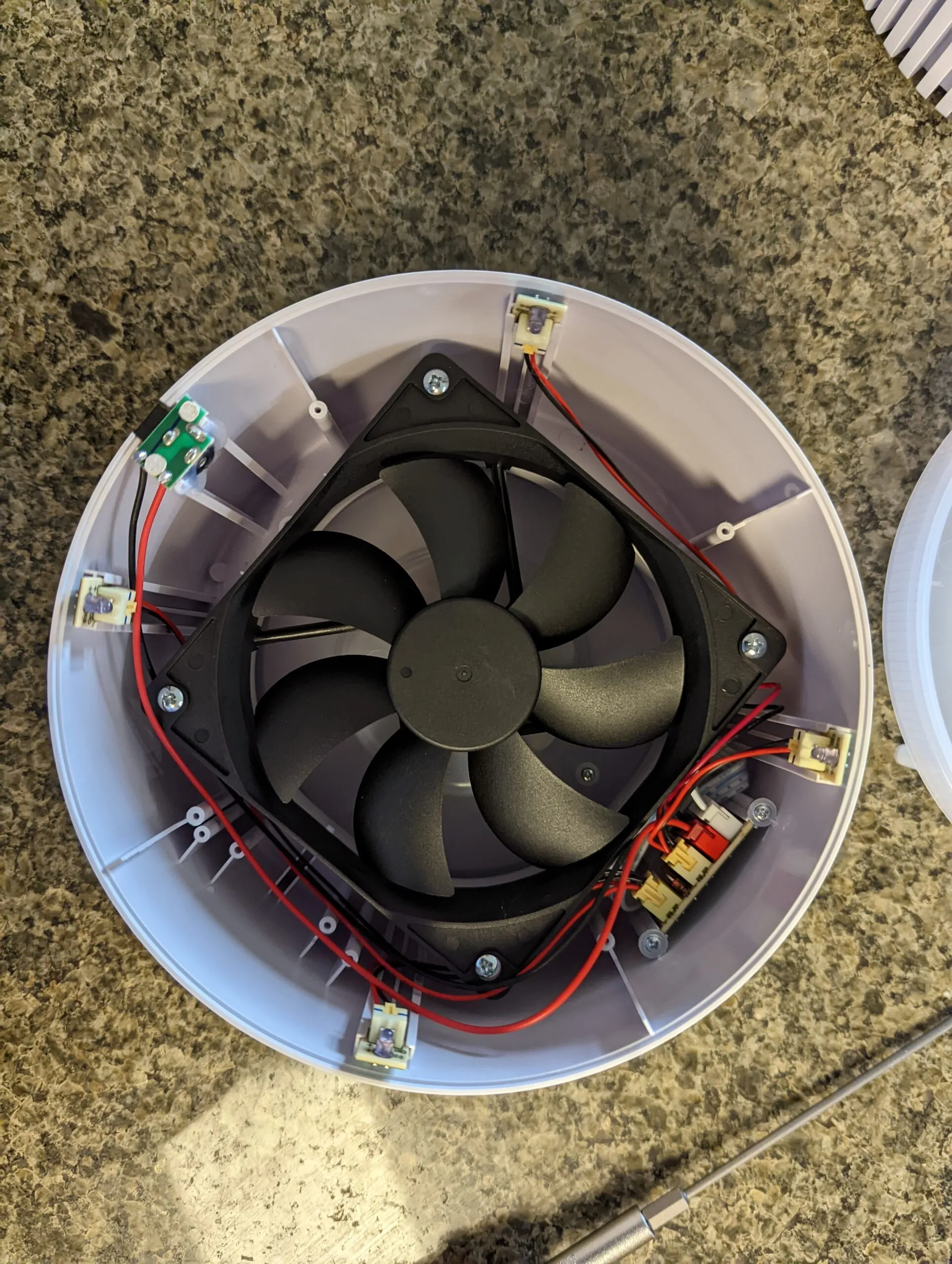 Inside the top half: a standard 120 mm PC fan ringed by the small LED boards for the base light ring, red and black wiring running to a little board on the wall
