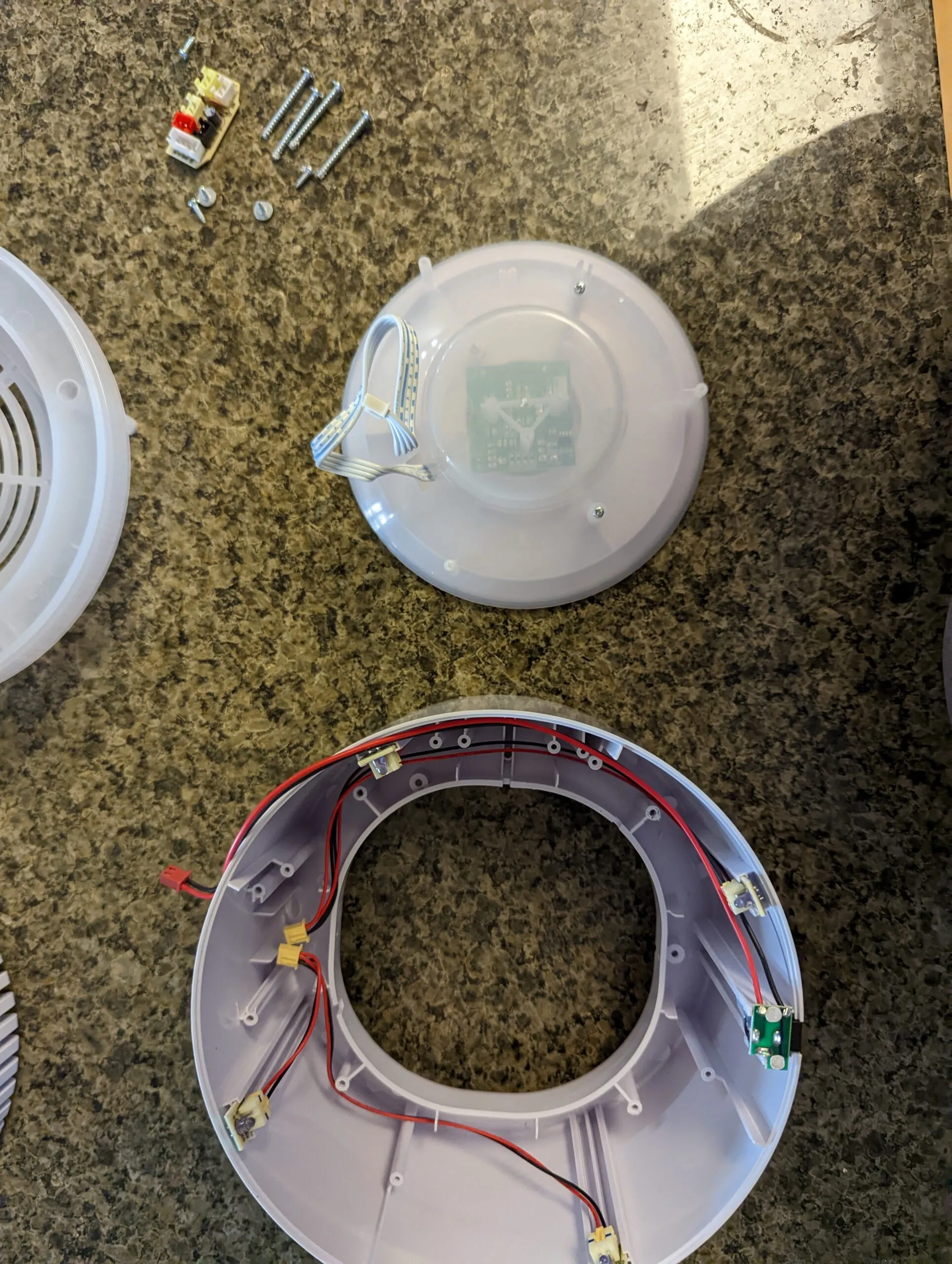 The Koios fully apart: control dome, LED ring, grille, and a pile of self-tappers