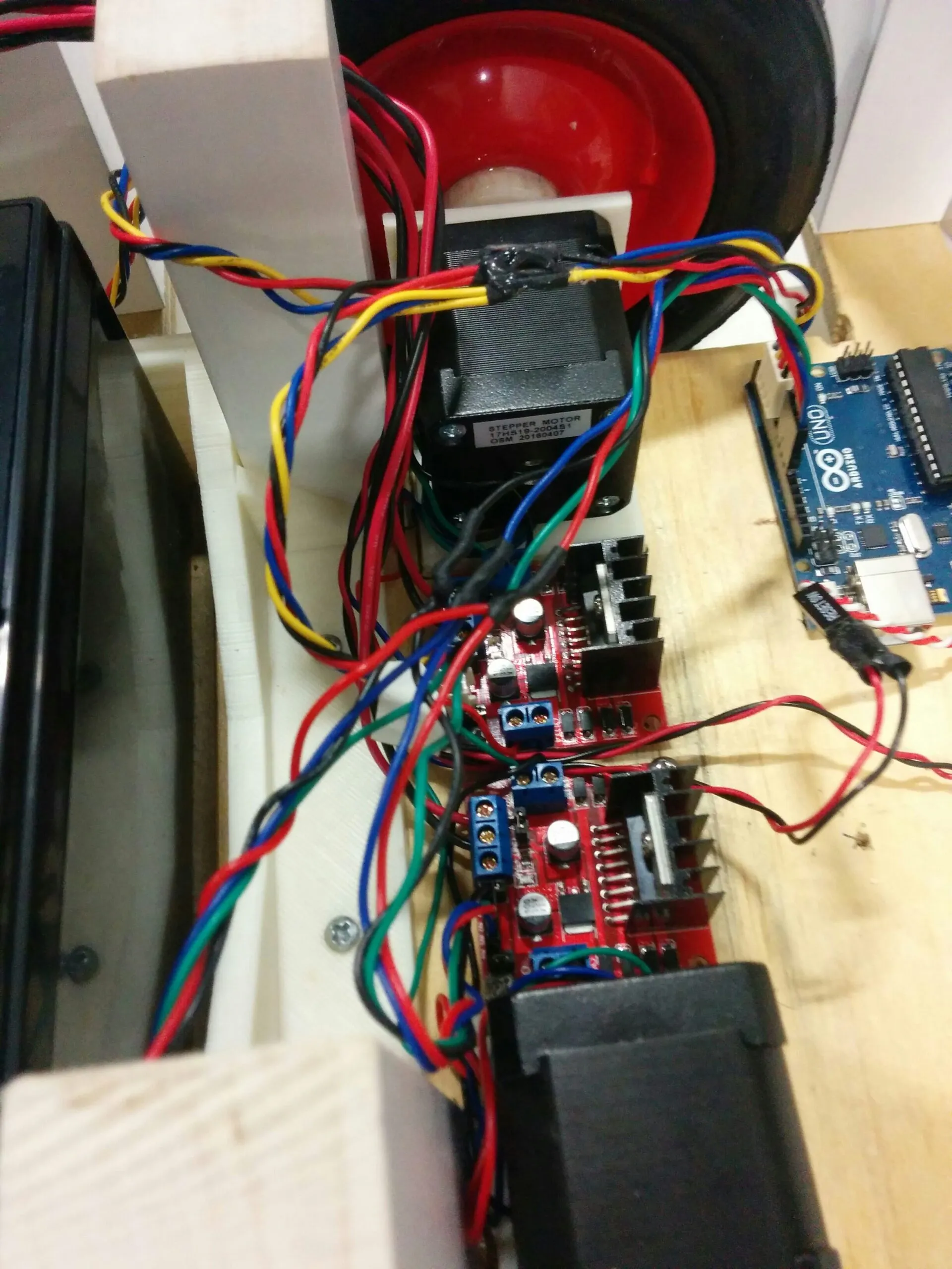Close-up of a NEMA 17 stepper (17HS19) and its L298N driver board, with the second stepper and board below and the Arduino Uno at the edge of frame
