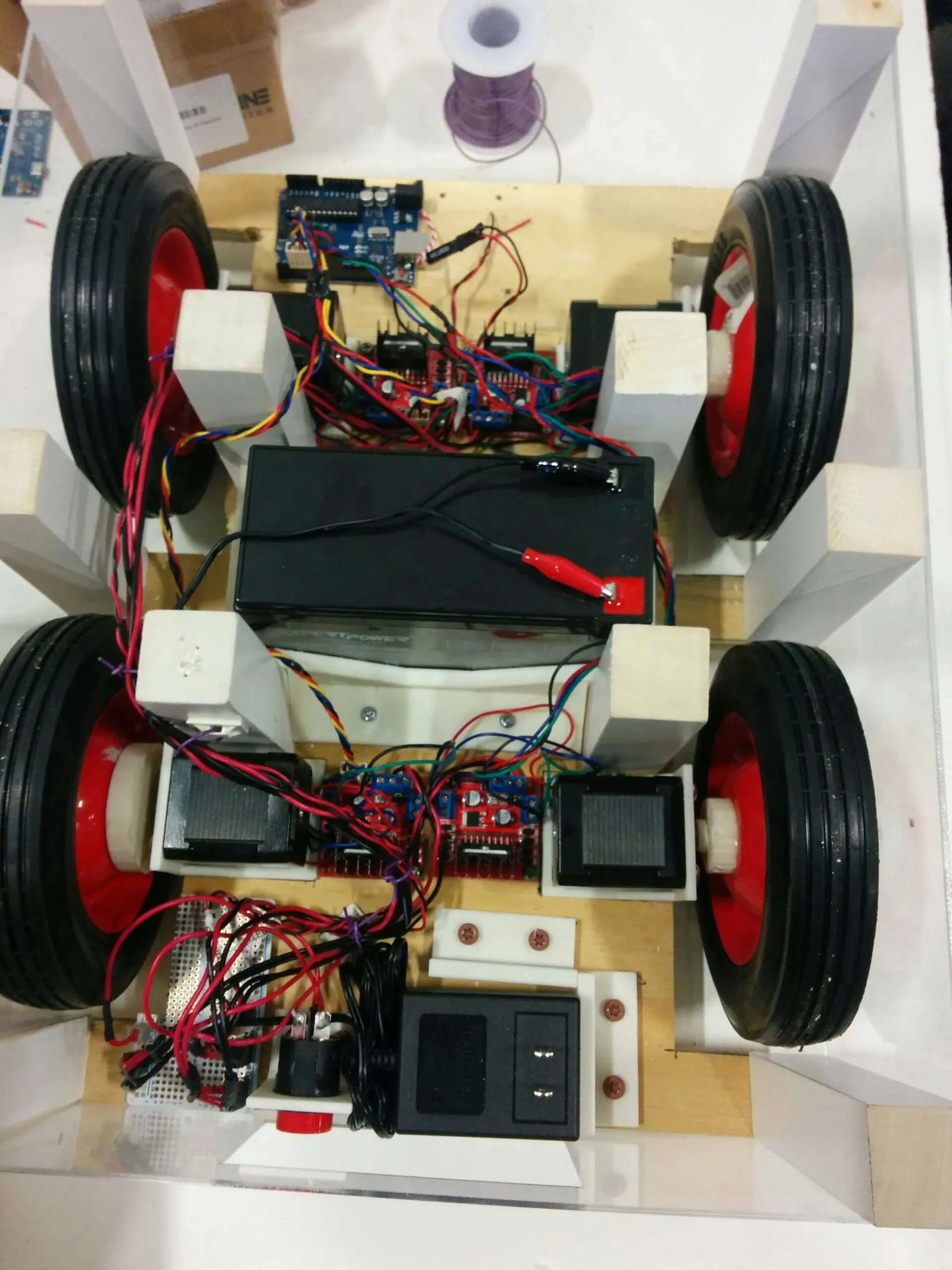 Orion wired end to end: Arduino up front, an L298N and stepper at each corner, SLA battery amidships, charger and e-stop at the tail
