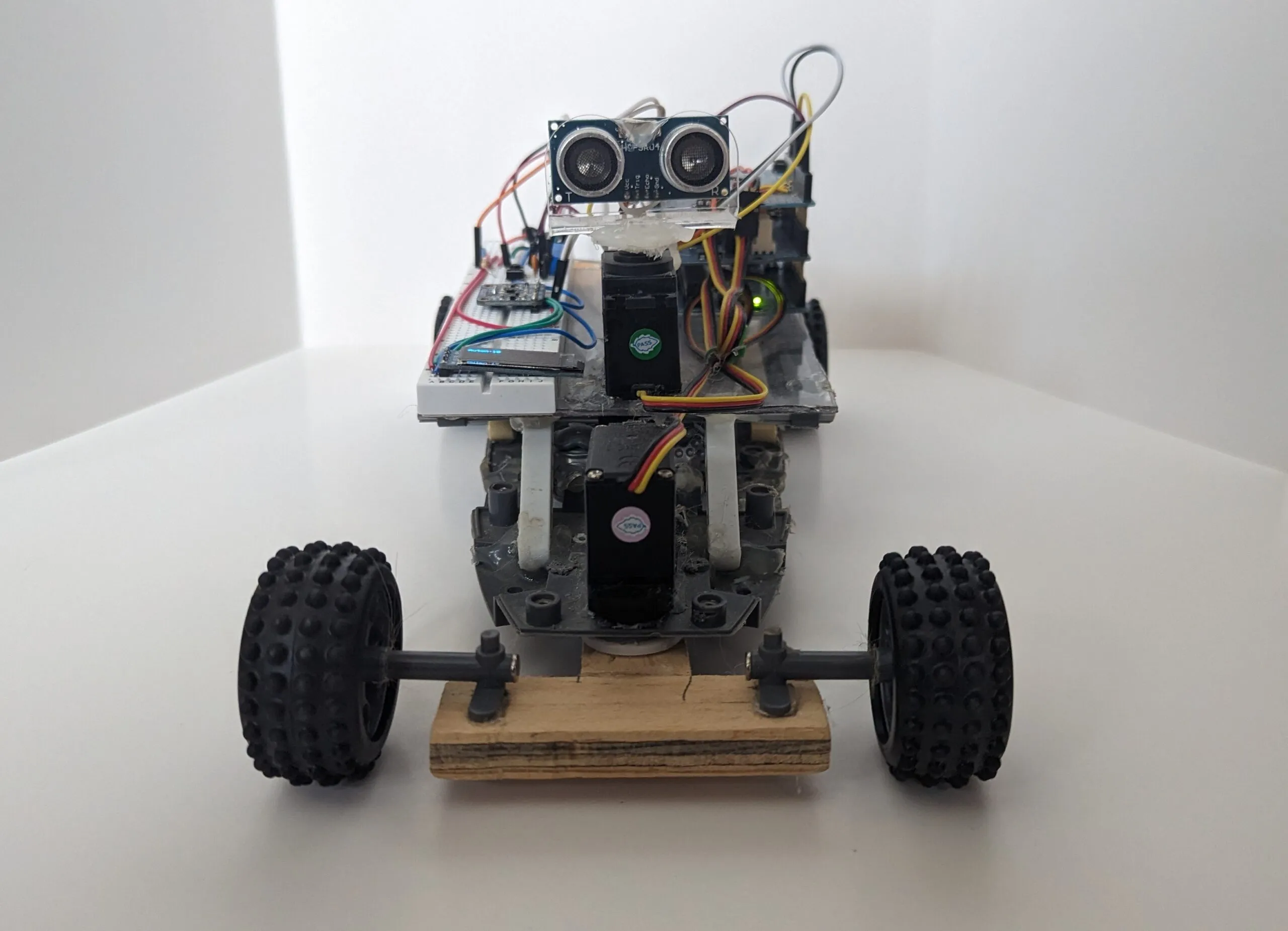 RoverBot head on: ultrasonic eyes on the head servo, steering servo beneath, LEGO wheels on the wooden axle