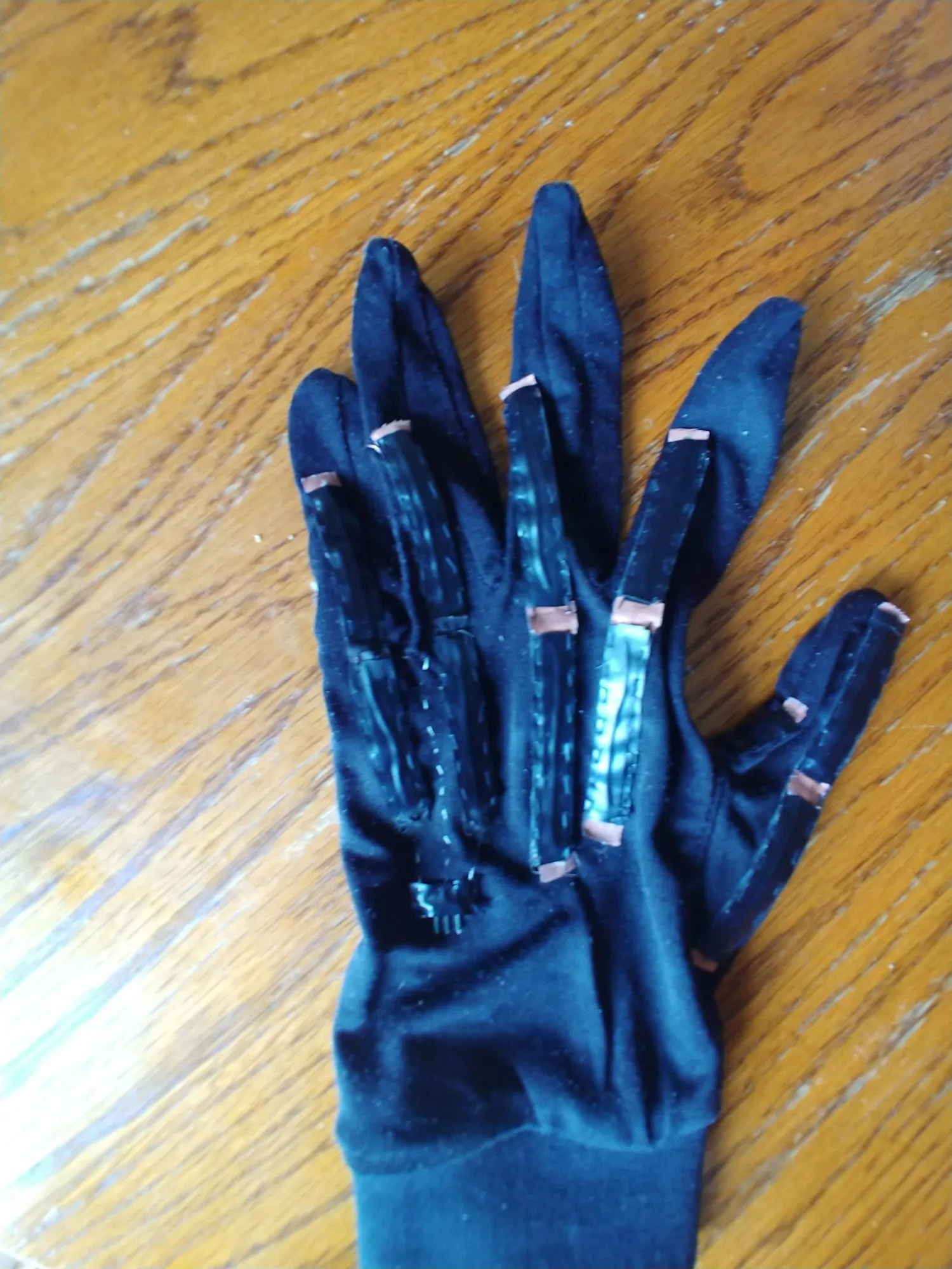 A blue glove with the home-made flex sensors sewn along each finger, foil contacts at the ends.