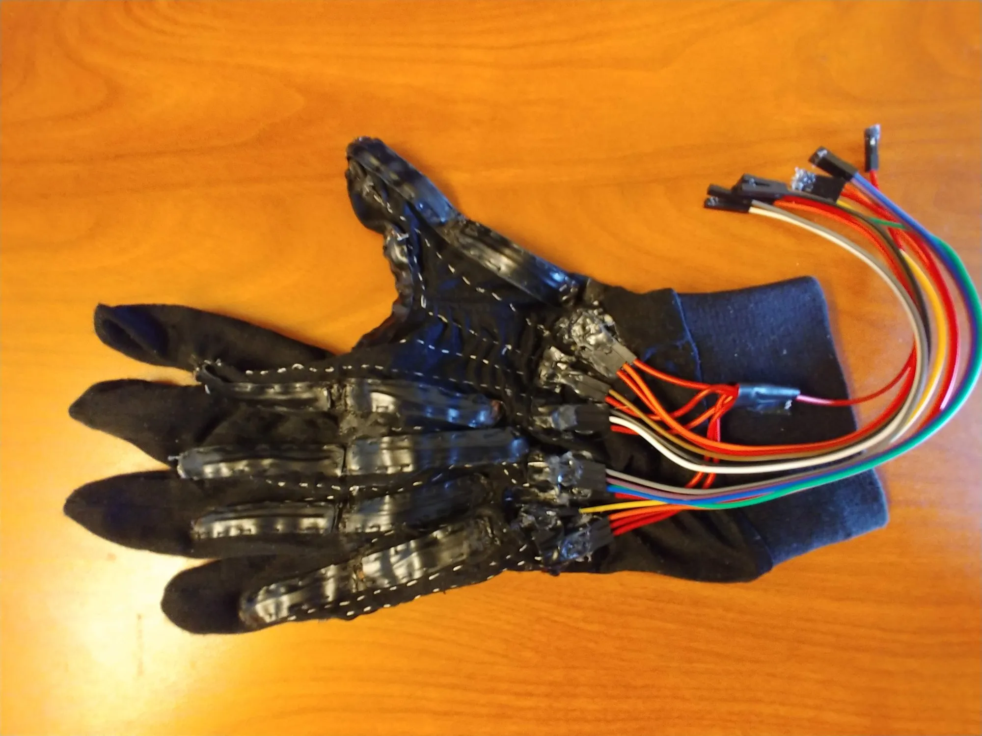 The version two sensing glove face up with all its sensor leads gathered at the wrist.