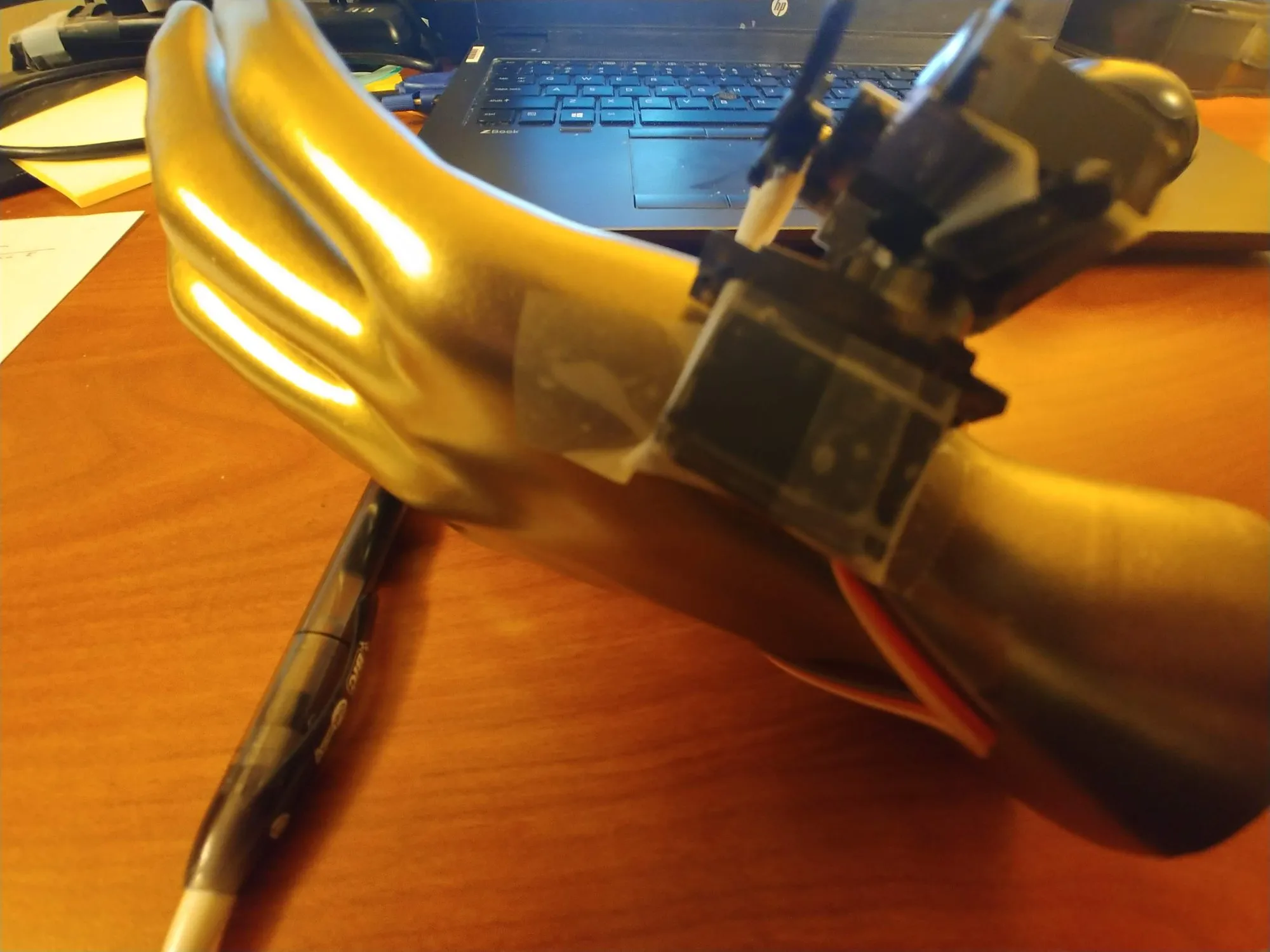 The mannequin hand from the wrist, the servo and finger mount strapped over it with tape.